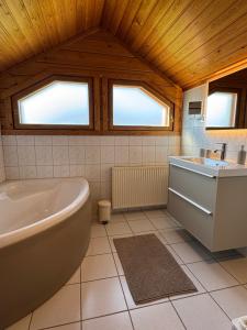 a bathroom with a tub and a sink and two windows at Finnische Blockhäuser in Gartow +22 photos