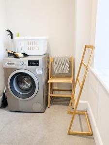 a laundry room with a washing machine and a chair at Steam Mill in Wellow