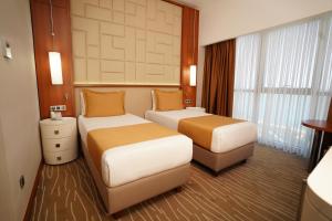 a hotel room with two beds and a window at Grand Bellagio Hotel Batumi in Batumi