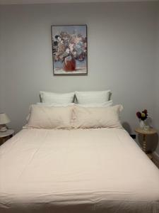 a bed with white sheets and a picture on the wall at The Bloom in Seaspray
