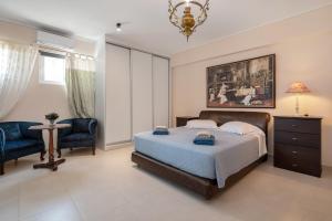 a bedroom with a bed and two chairs and a chandelier at Celeste Sea View Home with Jacuzzi and BBQ in Psalidi +117 photos