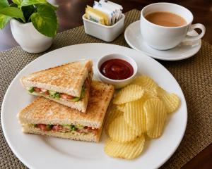 a sandwich and chips on a plate with a cup of coffee at Tree Heaven Resort-Kanatal in Kanatal