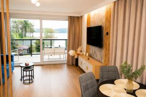 a living room with a television and a table with chairs at Ruciane Residence in Ruciane-Nida