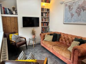 a living room with a brown couch and a tv at Secret City Cottage - Peaceful - Private Garden in Aberdeen