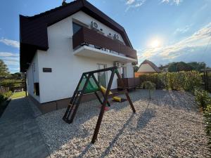 a playground in front of a house with a swing at Ady80 in Balatonmáriafürdő