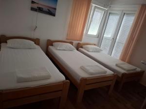 two twin beds in a room with two windows at Dara Apartmani in Donji Štoj