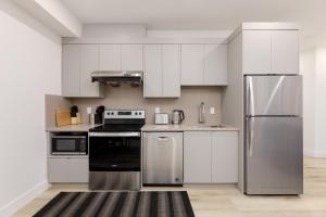 a kitchen with stainless steel appliances and white cabinets at Newly Built Suite-West Coquitlam in Coquitlam