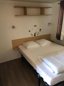 a bedroom with a bed with white sheets and butterflies on the wall at Mobilhome avec piscine in Ruoms +9 photos
