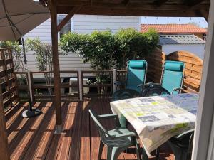 a table and chairs on a deck with an umbrella at Mobilhome avec piscine in Ruoms