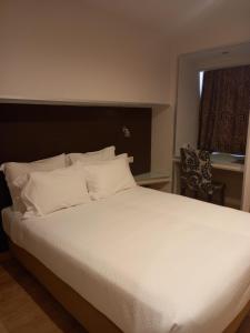 a bedroom with a large bed with white sheets and a window at Hotel Bocage in Setúbal