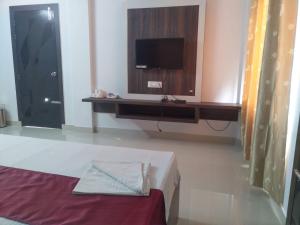 a bedroom with a bed and a tv on a wall at Boroli in Shaugaon