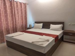 a bedroom with a large bed with a red curtain at Boroli in Shaugaon