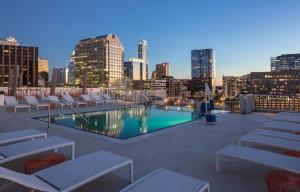 a rooftop pool with chairs and a city skyline at Austin Resort Studio Apartment in Austin
