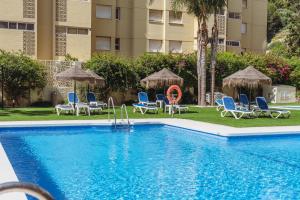 a swimming pool with chairs and umbrellas next to a building at Hotel Mainare Playa in Fuengirola