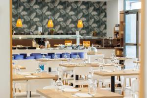 a restaurant with wooden tables and white chairs at Hotel Mainare Playa in Fuengirola