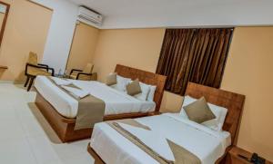 a hotel room with two beds and a window at Hotel Grand Heritage Badami in Badami
