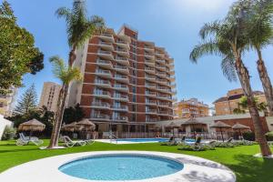 a large apartment building with a swimming pool and palm trees at Hotel Mainare Playa in Fuengirola