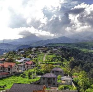 a village on a hill with mountains in the background at UNO-Dili Hotel includes free pick up and drop off in Dilijan