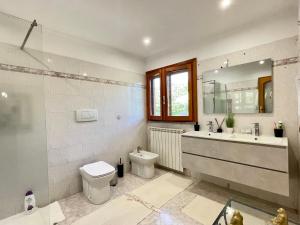 a bathroom with a toilet and a sink and a mirror at VILLA PRAXEDES con piscina a Nettuno in Nettuno +69 photos