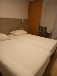 a large white bed in a room with a chair at Guesthouse Bocage in Setúbal +8 photos