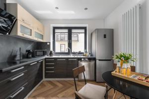 a kitchen with black cabinets and a stainless steel refrigerator at Cetyna Retreat - Dom w Beskidzie Sądeckim, 8 osób, szlaki, cisza, EV in Rytro