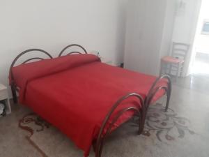 a red bed with a red blanket on it at Via Piave 14 in Santa Cesarea Terme