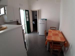 a kitchen and dining room with a table and a refrigerator at Via Piave 14 in Santa Cesarea Terme +1 photo