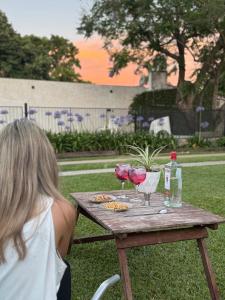 a woman sitting at a picnic table with wine glasses at Hospedaje Buena Vibra in San Nicolás de los Arroyos