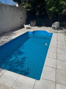 a blue swimming pool with a bench next to it at Hospedaje Buena Vibra in San Nicolás de los Arroyos