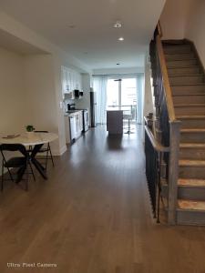 a living room with a staircase and a table and a kitchen at Lake breeze water view in Bowmanville