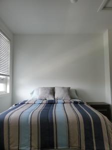 a bedroom with a bed with a striped blanket at Lake breeze water view in Bowmanville