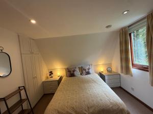a bedroom with a bed with two night stands and a window at Loch Oich Lodge in Invergarry