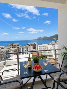 a table with wine glasses and a bowl of fruit on a balcony at Sunrise apartmani in Bar