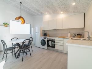 a kitchen with white cabinets and a table and chairs at Winahost Pla de Can Sans in Sant Andreu de Llavaneres