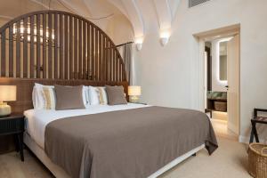 a bedroom with a large bed with a wooden headboard at Magno Collection Palacio de Becas in Seville