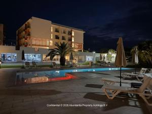 a swimming pool in front of a building at night at studio to Maho in Cupecoy