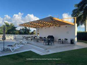 a patio with tables and chairs under a pergola at studio to Maho in Cupecoy