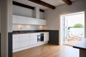 a kitchen with white cabinets and a sliding glass door at Westergaards Hotel in Videbæk