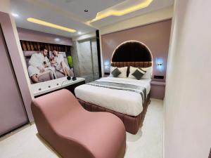 a hotel room with a large bed and a chair at Hotel Pacific Empire in Ahmedabad