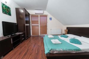 a bedroom with a large bed and a flat screen tv at Pensiunea Gerard 2 Mai Camere Moderne cu baie privata, la 250 M de plaja ,Foisor, Parcare & WIfi Gratuit in 2 Mai