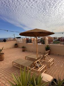 a patio with two chairs and an umbrella at NOUR Tamraght in Tamraght Ouzdar