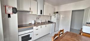 a kitchen with white cabinets and a wooden table at Maré Viva in Quarteira