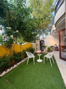 a patio with two chairs and a table on grass at The pink villa in Jaipur