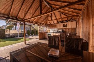 a patio with a table and chairs under a wooden roof at Pensiunea Gerard 2 Mai Camere Moderne cu baie privata, la 250 M de plaja ,Foisor, Parcare & WIfi Gratuit in 2 Mai
