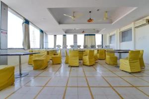 a room with yellow chairs and tables and windows at FabHotel Jaipur Classic - Vaishali Nagar in Jāmb