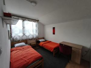a room with two beds and a desk and a window at Hideout Guest House in Travnik