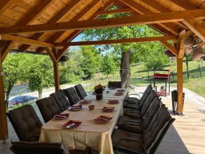 a long table and chairs under a wooden roof at Apartments Daisy in Banja Luka