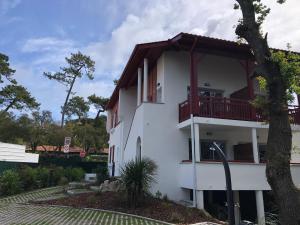 a white building with a balcony and a tree at Villa Bambous 1 et 2 in Hossegor