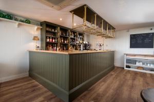 a bar in a restaurant with a green wall at Beach House Hotel in Seahouses