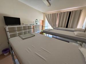 a room with two bunk beds and a tv at Garden Hostel in Aradas